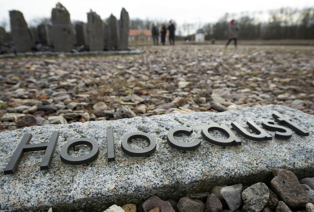 people walk behind the writing 'Holocaust' during the international Holocaust remembrance day in the former the Nazi concentration camp Buchenwald