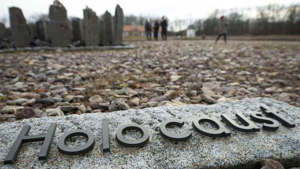 people walk behind the writing 'Holocaust' during the international Holocaust remembrance day in the former the Nazi concentration camp Buchenwald