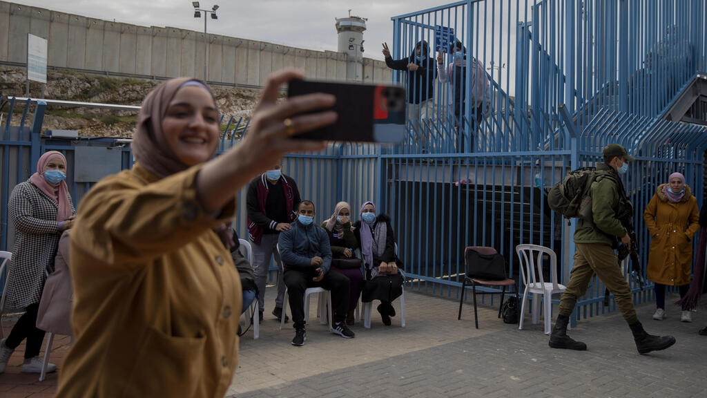 Palestinians take a selfie after receiving the coronavirus vaccine from an Israeli medical team at the Qalandia checkpoint between the West Bank and Jerusalem, Feb. 23, 2021 