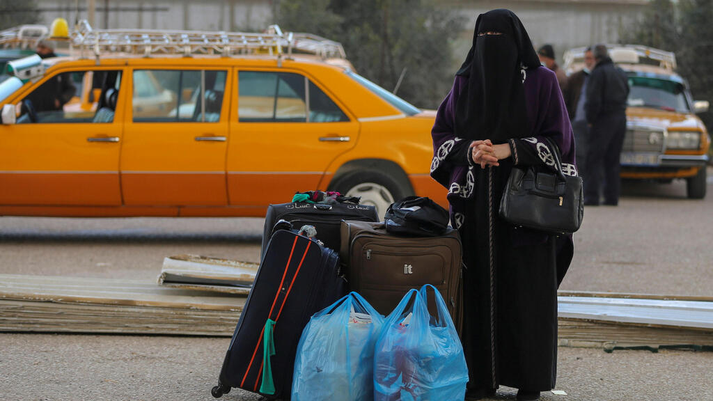 A Palestinian woman waits to leave Gaza through Rafah border crossing with Egypt,