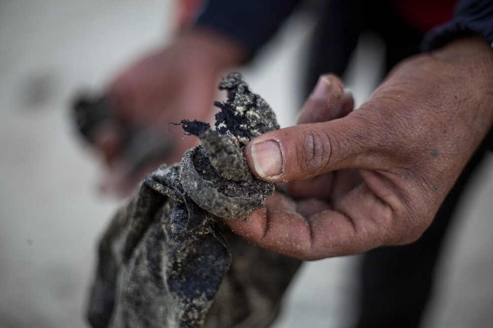 A local fisherman who goes by the name Jumbo holds tar that washed on to the docks from an oil spill in the Mediterranean Sea, in the Israeli Arab village of Jisr al-Zarqa 