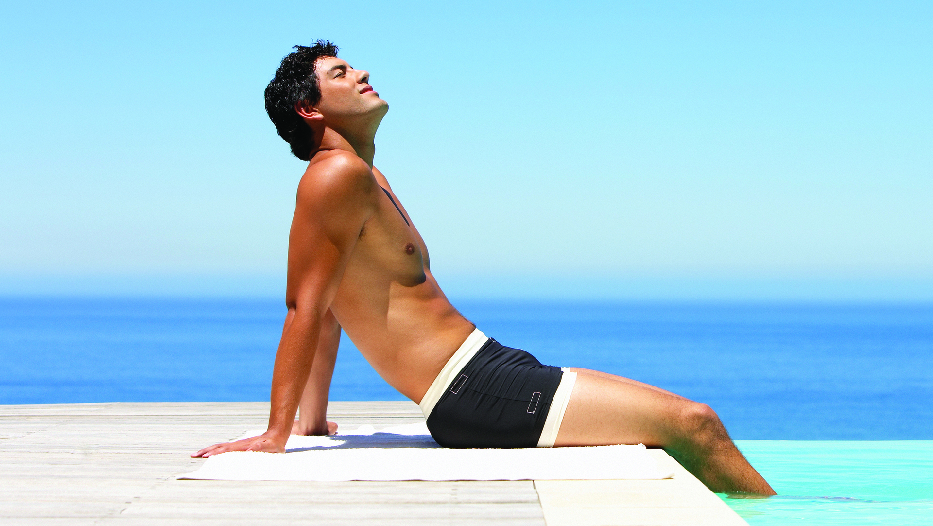 איש יושב על שפת הבריכה