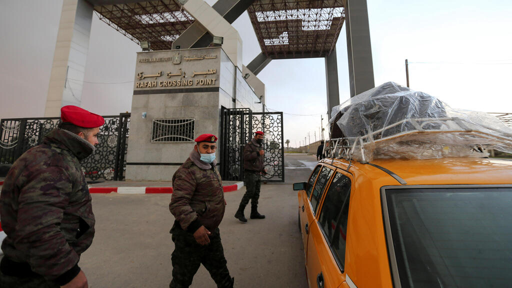 embers of Palestinian security forces keep watch as a taxi carrying passengers arrives at the gate of Rafah border crossing with Egypt, in the southern Gaza Strip