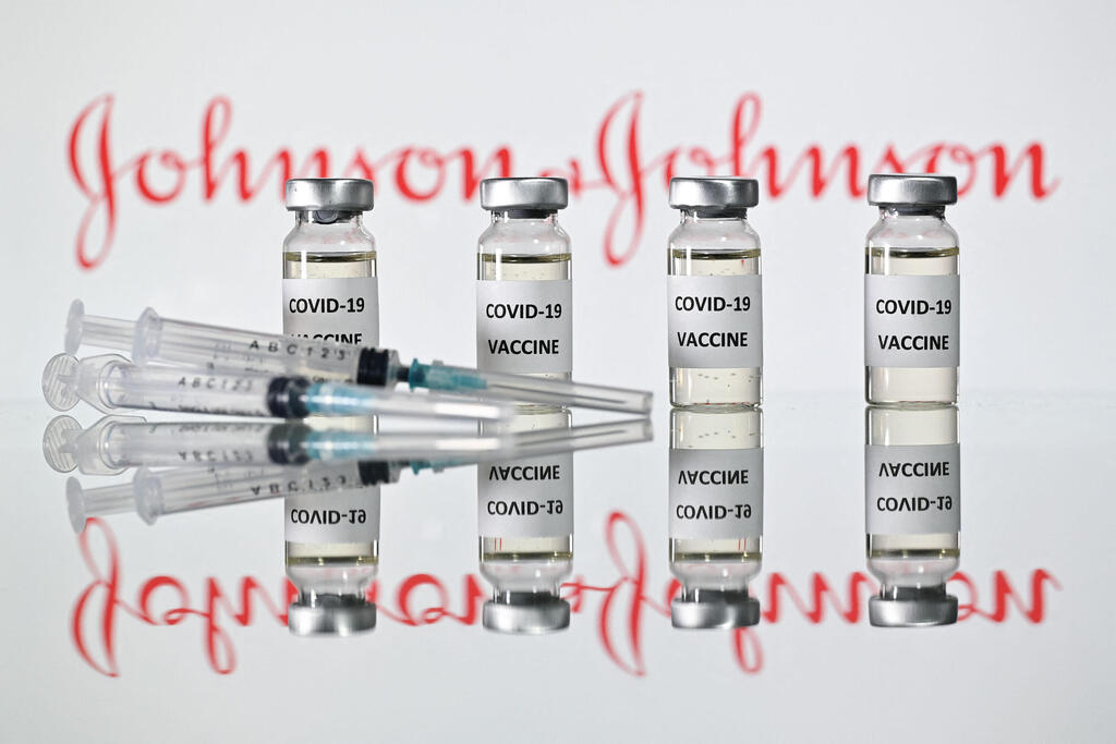 Vials with COVID-19 vaccine stickers, syringes and the logo of Johnson & Johnson  