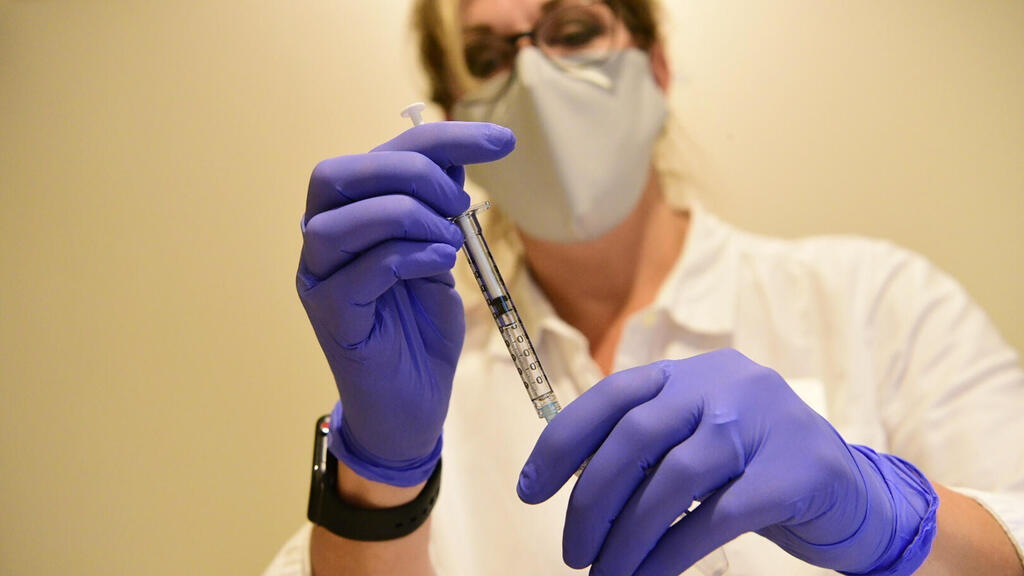 A  a pharmacist  prepari g to administrate J&J's COVID-19 vaccine