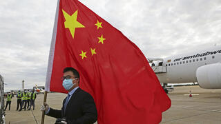 עם דגל סין מול מטוס עמוס מנות חיסון נגד קורונה של סינופארם בשדה תעופה ב זימבבואה