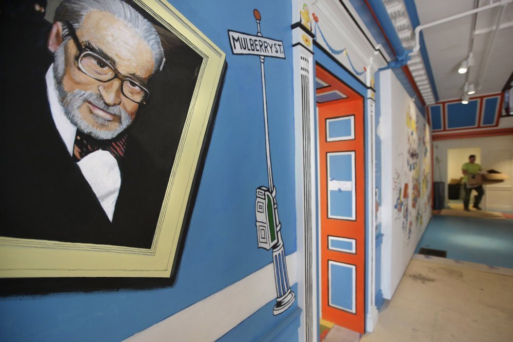 a mural that features Theodor Seuss Geisel, left, also known by his pen name Dr. Seuss, covers part of a wall near an entrance at The Amazing World of Dr. Seuss Museum, in Springfield, Mass. 