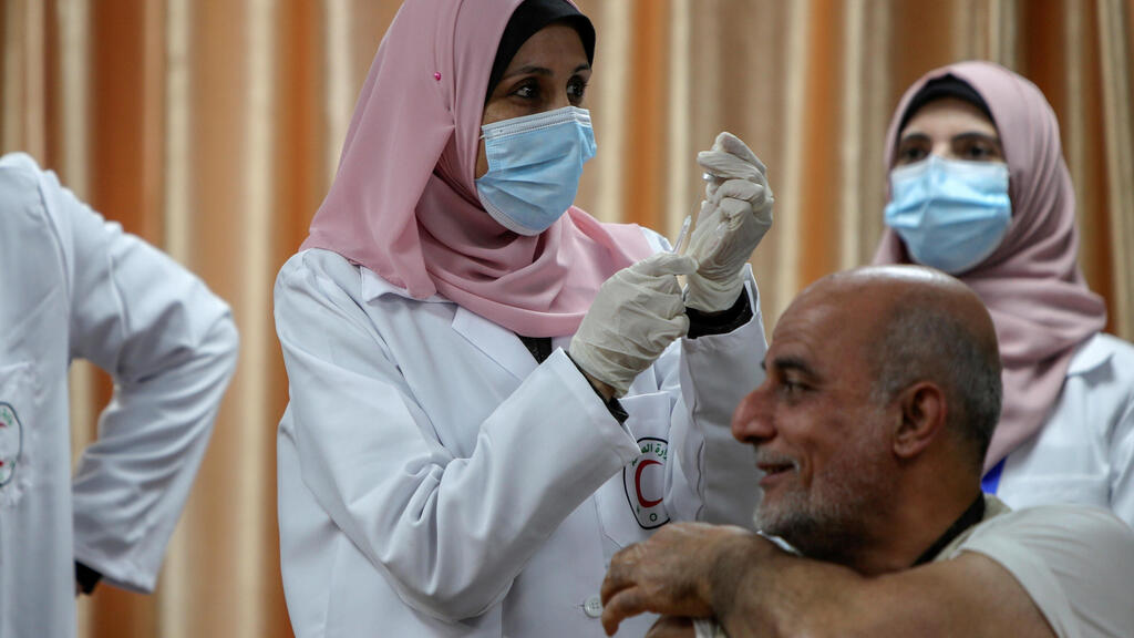 : A health worker prepares to vaccinate former Palestinian health minister Jawad Tibi against the coronavirus disease
