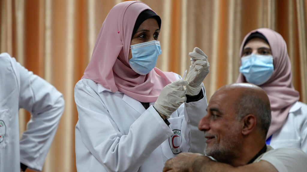 : A health worker prepares to vaccinate former Palestinian health minister Jawad Tibi against the coronavirus disease