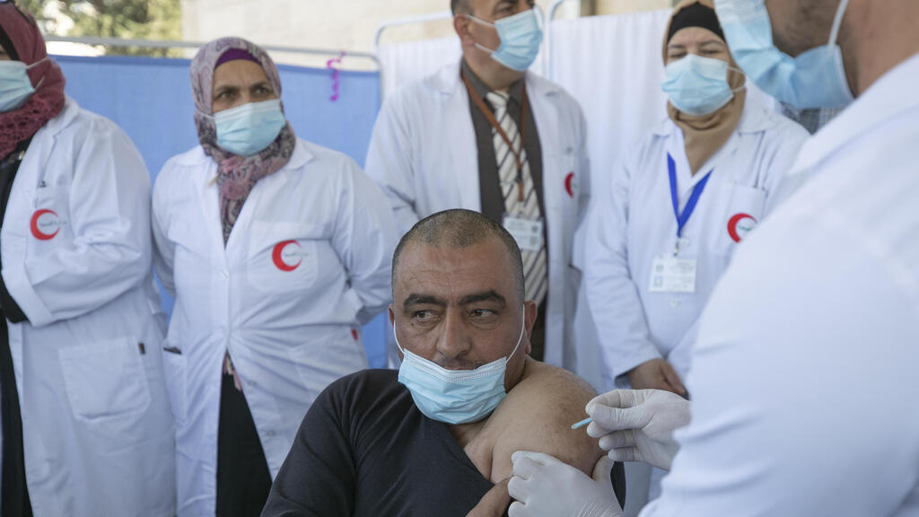 Medic administers a Moderna COVID-19 vaccine to a fellow medic during a campaign to vaccinate front-line medical workers, at the health ministry, in the West Bank city of Bethlehem 