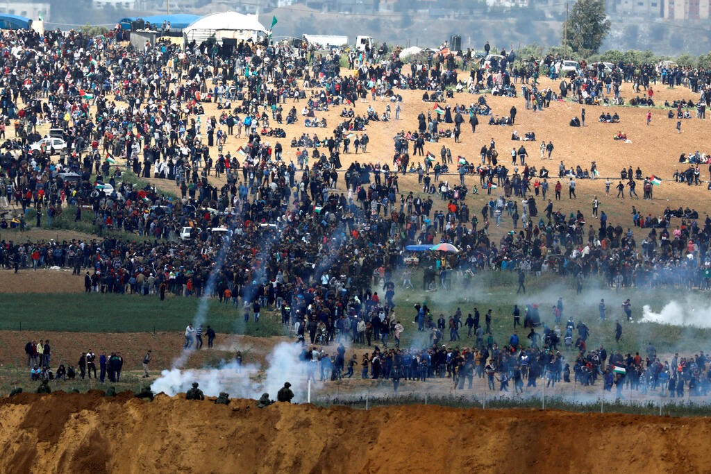 Israeli soldiers shoot tear gas from the Israeli side of the Israel-Gaza border as Palestinians protest on the Gaza side of the border, March 30, 2018