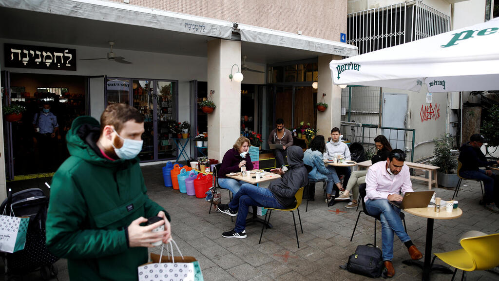Guests sit and take away food and drinks from a Tel Aviv cafe as Israel further the eases coronavirus restrictions, March 7, 2021 