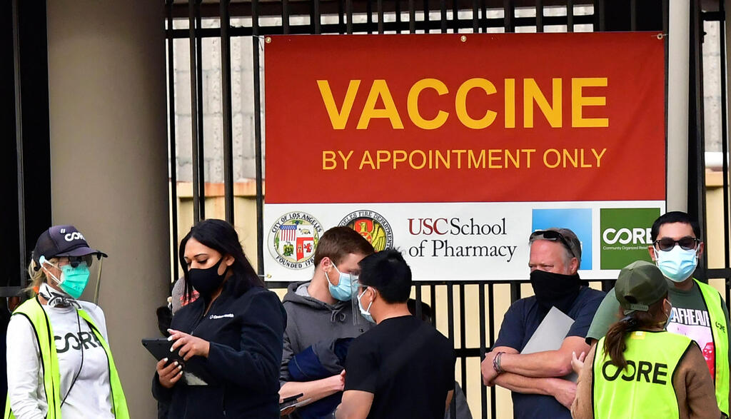 o people wearing facemasks are seen in front of a Covid-19 vaccination facility in Los Angeles 