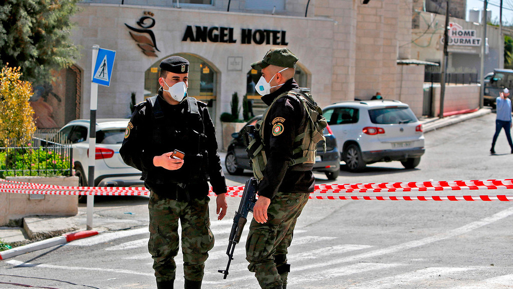 Palestinian police stand outside the Angel Hotel in Beit Jala at the start of the pandemic 