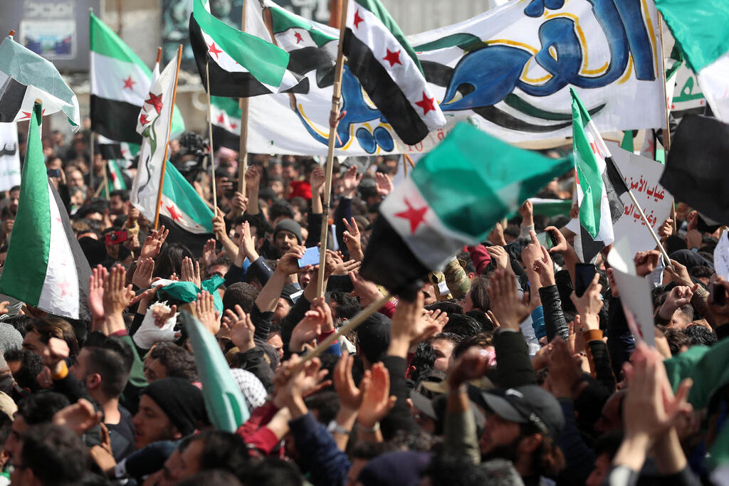 Protesters wave flags of the Syrian opposition during a demonstration in Syria's rebel-held city of Idlib