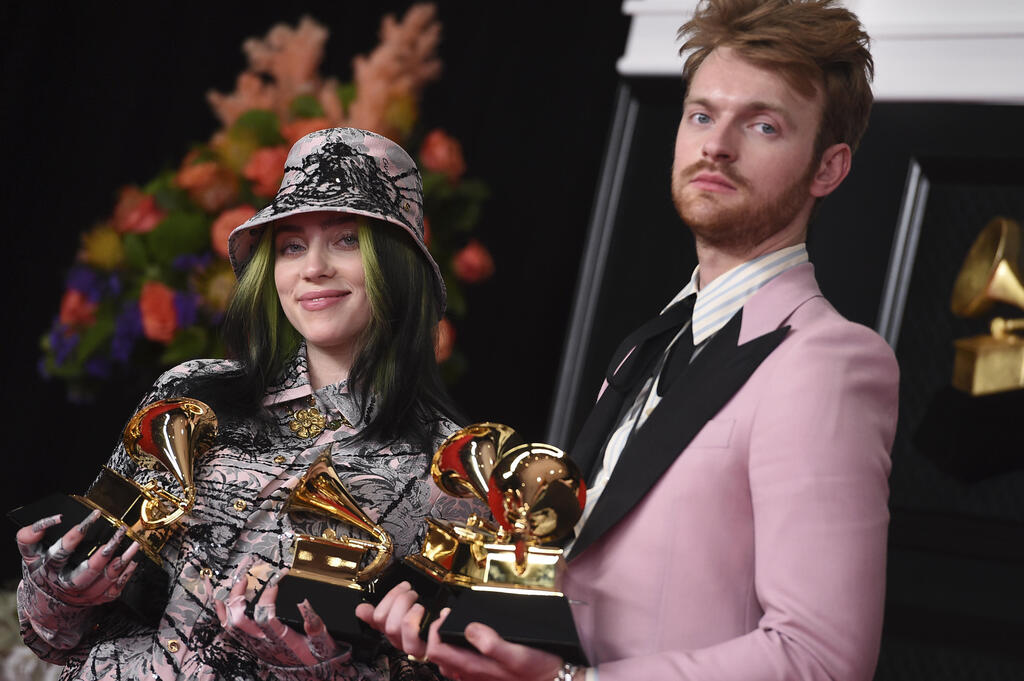 Finneas, left, and Billie Eilish pose in the press room with the awards for best song written for visual media and record of the year at the 63rd annual Grammy Awards at the Los Angeles Convention Center 