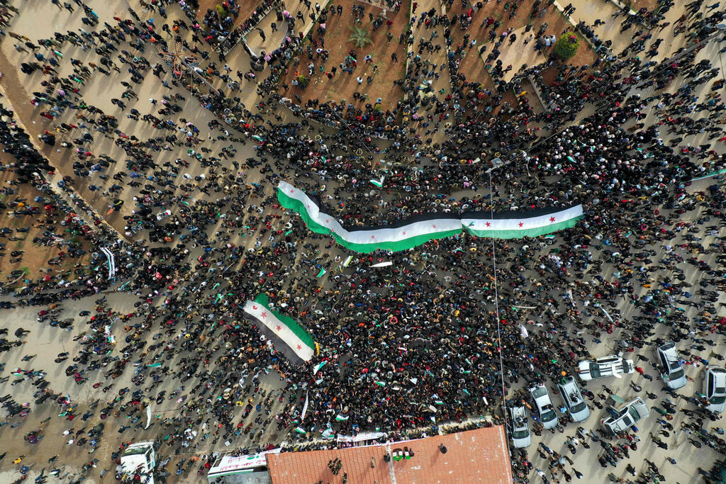 Syrians waving the opposition flag during a gathering in the rebel-held city of Idlib on March 15, as they mark ten years to beginning of civil war 
