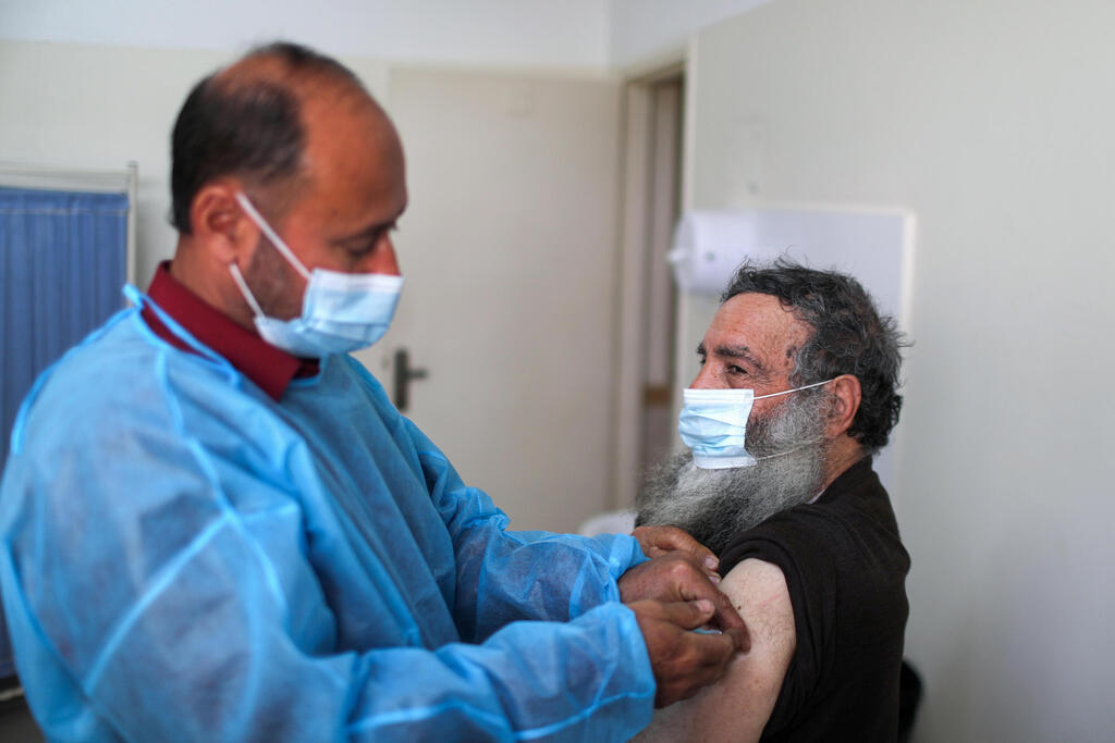 A health worker vaccinates a Palestinian man against the coronavirus disease (COVID-19), in Gaza City 