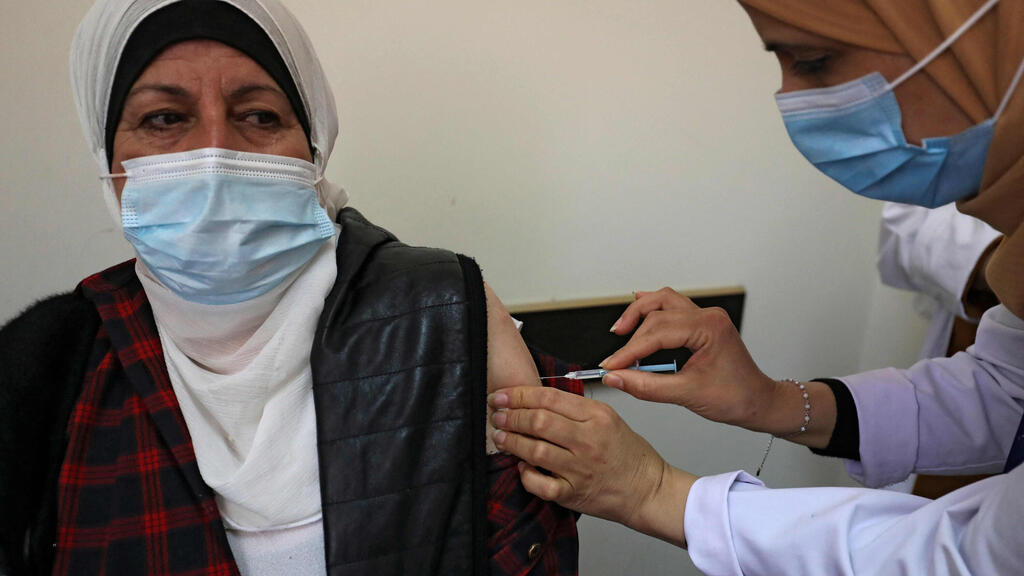A Palestinian healthcare worker administers the COVID-19 vaccine to a patient 