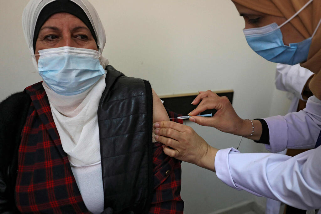A Palestinian healthcare worker administers the COVID-19 vaccine to a patient 