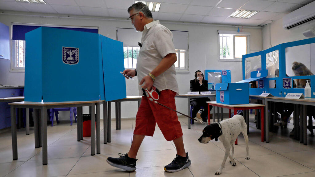 An Israeli man leads his dog as he casts his ballot at a polling station in Tel Aviv on March 23, 2021 