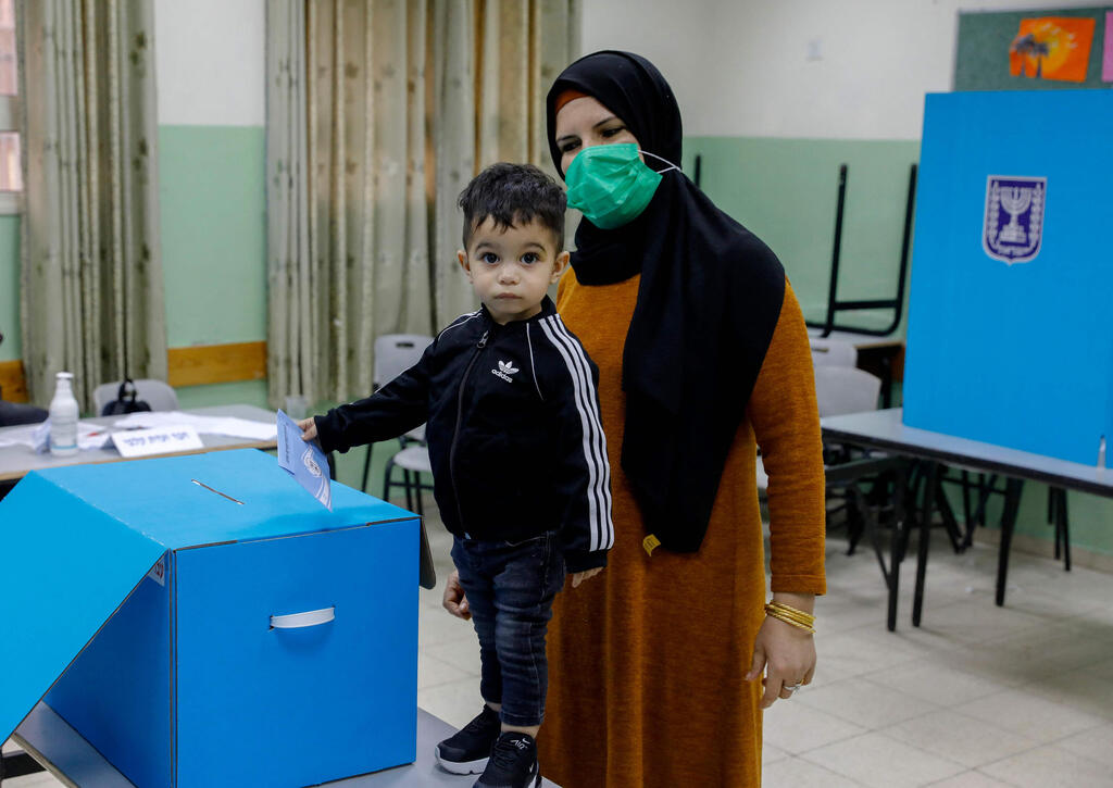 An Israeli Arab woman casts her vote in the March 23, 3021 elections in the town of Kfar Manda near Nazareth 