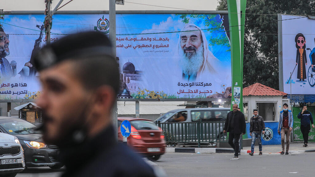 Palestinians walk next to a large poster of Hamas late leader Sheikh Ahmad Yassin during the 17th anniversay of his death in the streets of Gaza City 