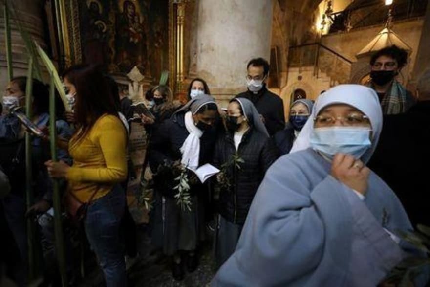 Christian worshippers and nuns hold palm fronds during a Palm Sunday procession in the Church of the Holy Sepulchre in Jerusalem 