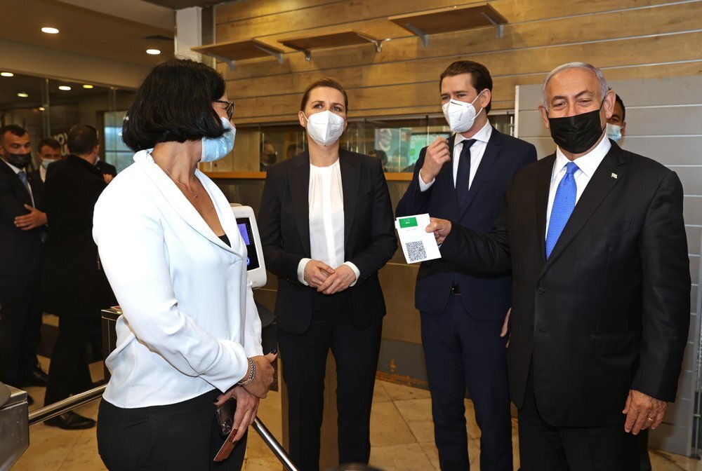 Prime Minister Benjamin Netanyahu, right, holds a "Green Pass," for citizens vaccinated against COVID-19, as he visits a fitness gym with Austrian Chancellor Sebastian Kurz, second right, and Danish Prime Minister Mette Frederiksen, left, to observe how the pass is used, in Modi'in 