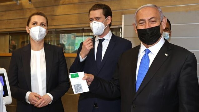Prime Minister Benjamin Netanyahu, right, holds a "Green Pass," for citizens vaccinated against COVID-19, as he visits a fitness gym with Austrian Chancellor Sebastian Kurz, second right, and Danish Prime Minister Mette Frederiksen, left, to observe how the pass is used, in Modi'in 