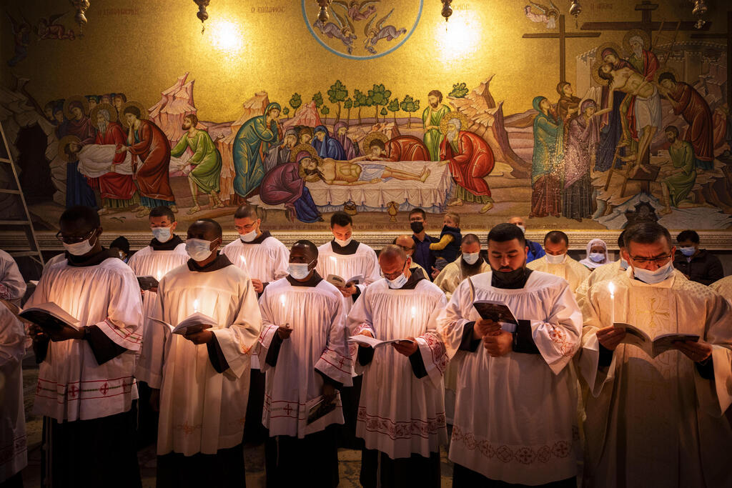 Priests wearing face masks pray during Easter Sunday Mass led by the Latin Patriarch at the Church of the Holy Sepulchre in the Old City of Jerusalem, April 4, 2021 