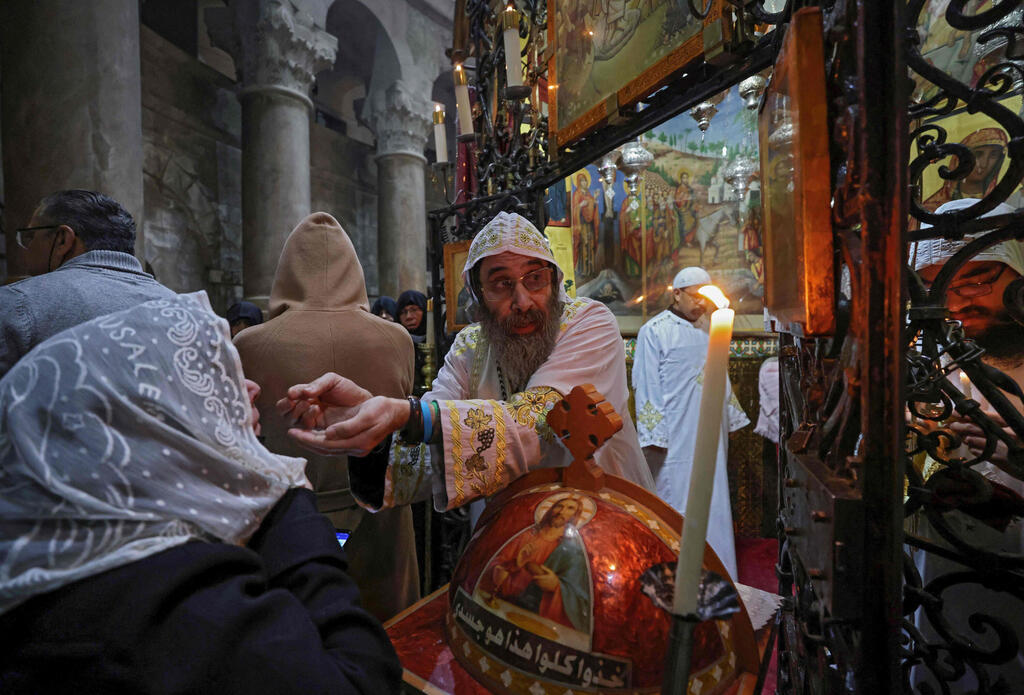 A Coptic priest gives the communion during mass on Easter Sunday at the Church of the Holy Sepulchre in Jerusalem on April 4, 2021 