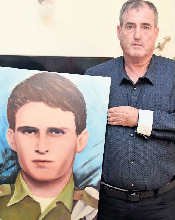 Oren Tamam holds a portrait of his late brother, Moshe