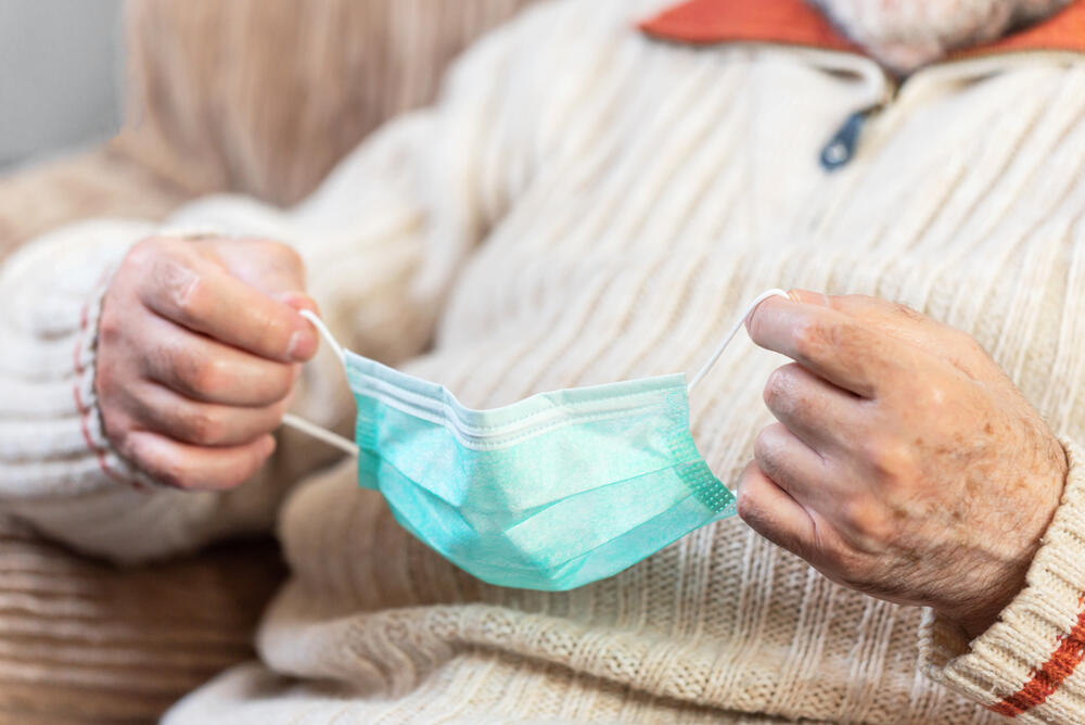 An elderly woman holding a facemask 