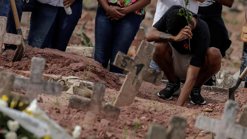 Mourners at a Brazil cemetery at the graves of family members who died of COVID-19 (Photo: EPA) Mourners at a Brazil cemetery at the graves of family members who died of COVID-19