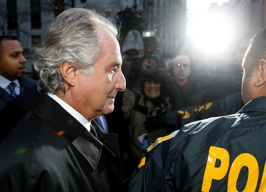 Disgraced financier Bernard Madoff is escorted by police and photographed by the media as he departs U.S. Federal Court after a hearing in New York, January 5, 2009 