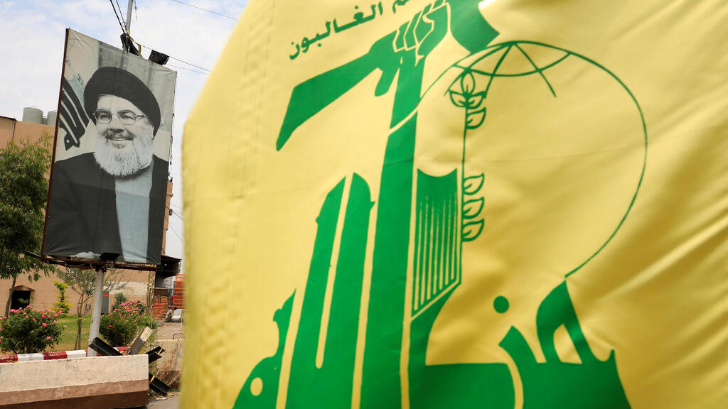 Hezbollah flag (Photo: Reuters) דגל חיזבאללה על רקע שלט ועליו נסראללה