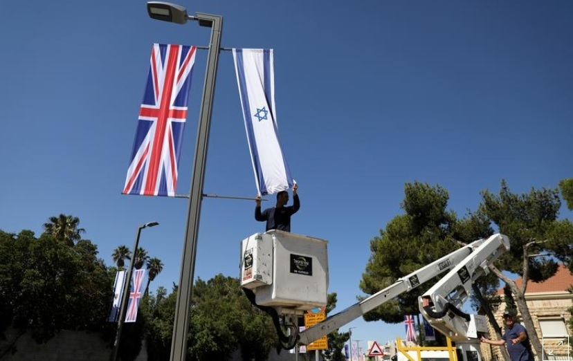 A Jerusalem municipality worker hangs an Israeli flag next to the British flag, the Union Jack, as he stands on a platform near Israel's presidential residence in Jerusalem ahead of the upcoming visit of Britain's Prince William, June 25, 2018