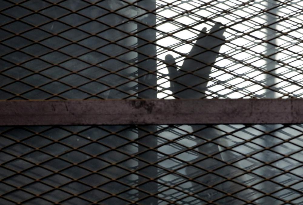 A member of the Muslim Brotherhood waves his hand from a defendants cage in a courtroom in Torah prison, southern Cairo, Egypt 