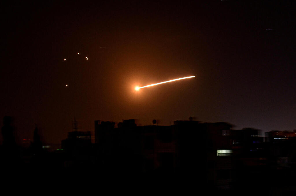 A streak of light is seen in the night sky in the vicinity of the Syrian capital Damascus during what Syrian authorities said was an Israeli air strike 