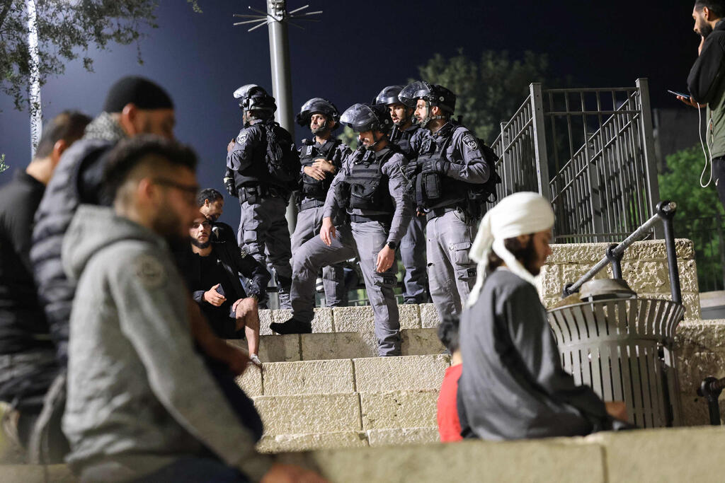 Israeli security forces stand beside Palestinians praying at the Damascus Gate entrance to the Old City of Jerusalem on Saturday (Photo: AFP) המשטרה מפזרת מפגינים באזור שער שכם בירושלים באמצעות רימוני הלם ופרשים