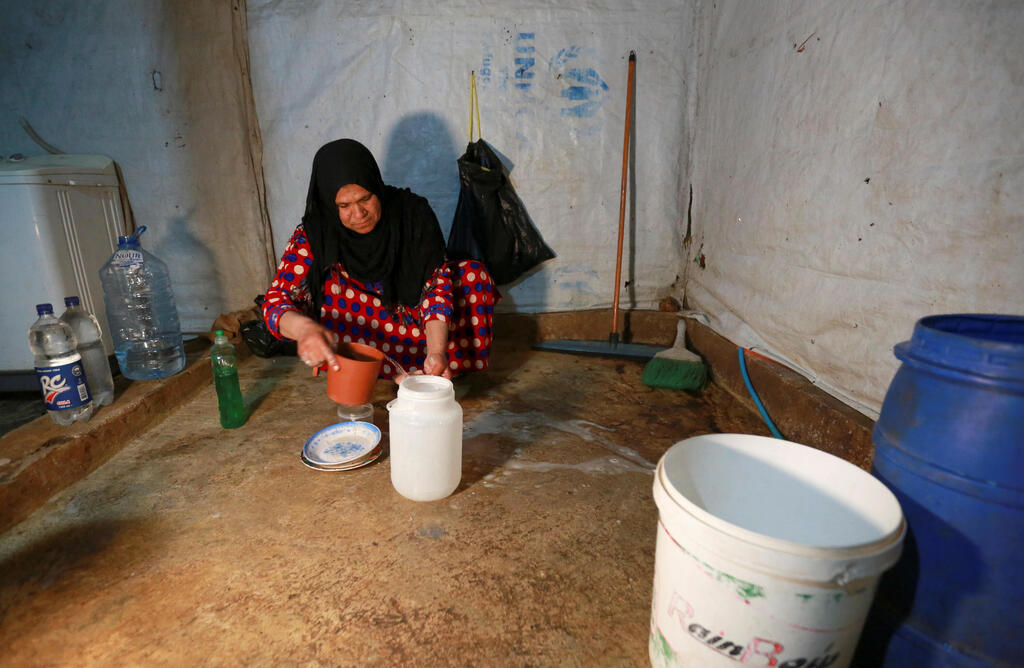 Um Ahmad, Hussein al-Khaled's wife, washes dishes inside a tent at an informal tented settlement in Bar Elias, in the Bekaa Valley, Lebanon April 22, 2021