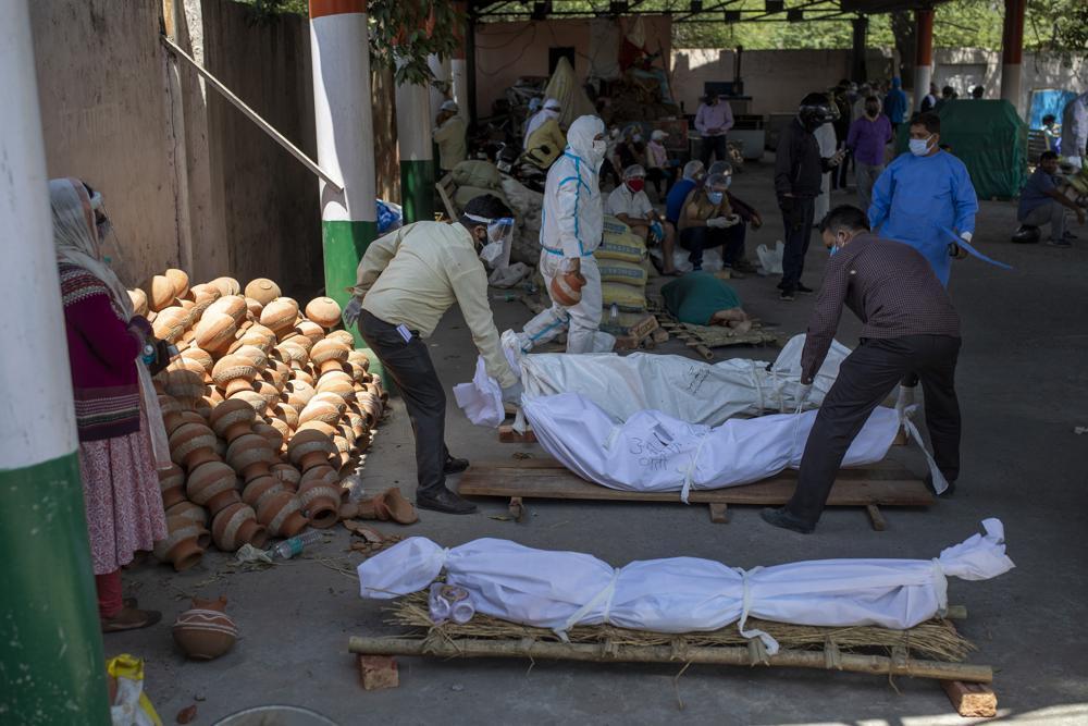 People line up dead bodies of those who died of COVID-19 at a crematorium, in New Delhi, India 