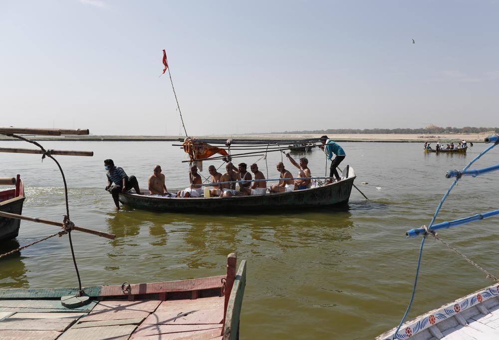 Hindus arrive to immerse the ashes of their relative who died of COVID-19 at the confluence of rivers Ganges and Yamuna, sacred to them, in Prayagraj, India 