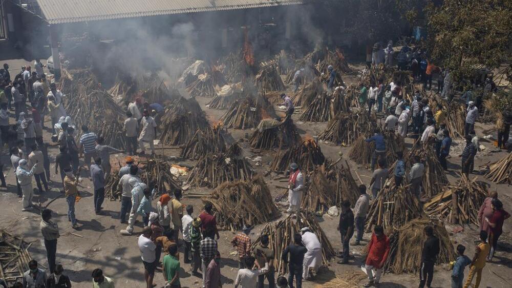 Multiple funeral pyres of those who died of COVID-19 burn at a ground that has been converted into a crematorium for the mass cremation of coronavirus victims, in New Delhi, India 