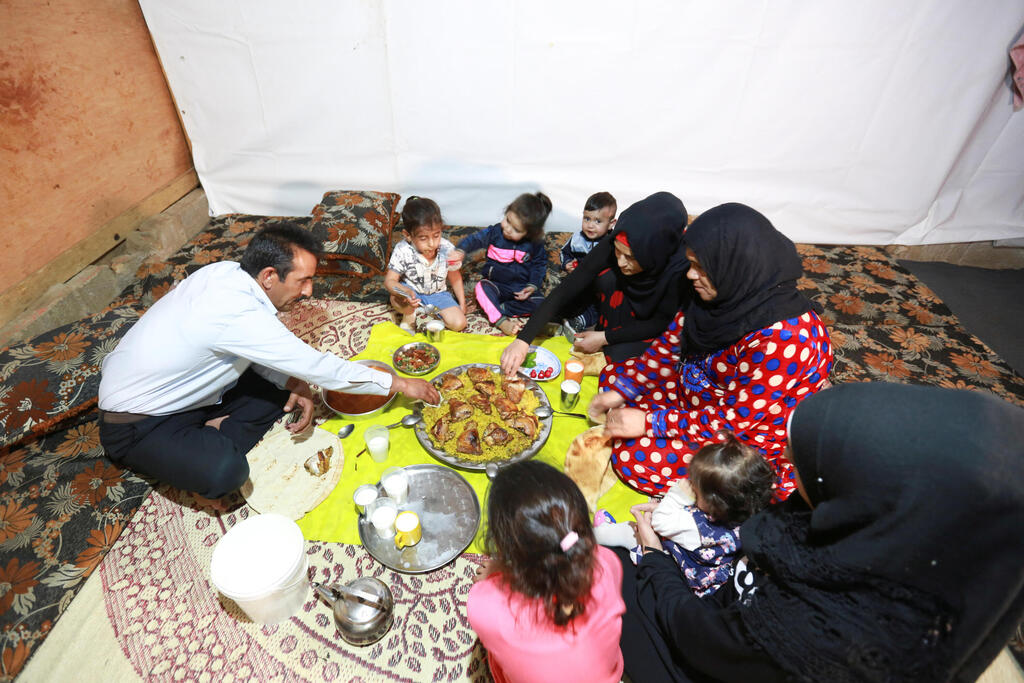 Hussein al-Khaled and his family eat their Iftar (breaking fast) meal during the holy month of Ramadan inside a tent at an informal tented settlement in Bar Elias, in the Bekaa Valley, Lebanon April 22, 2021