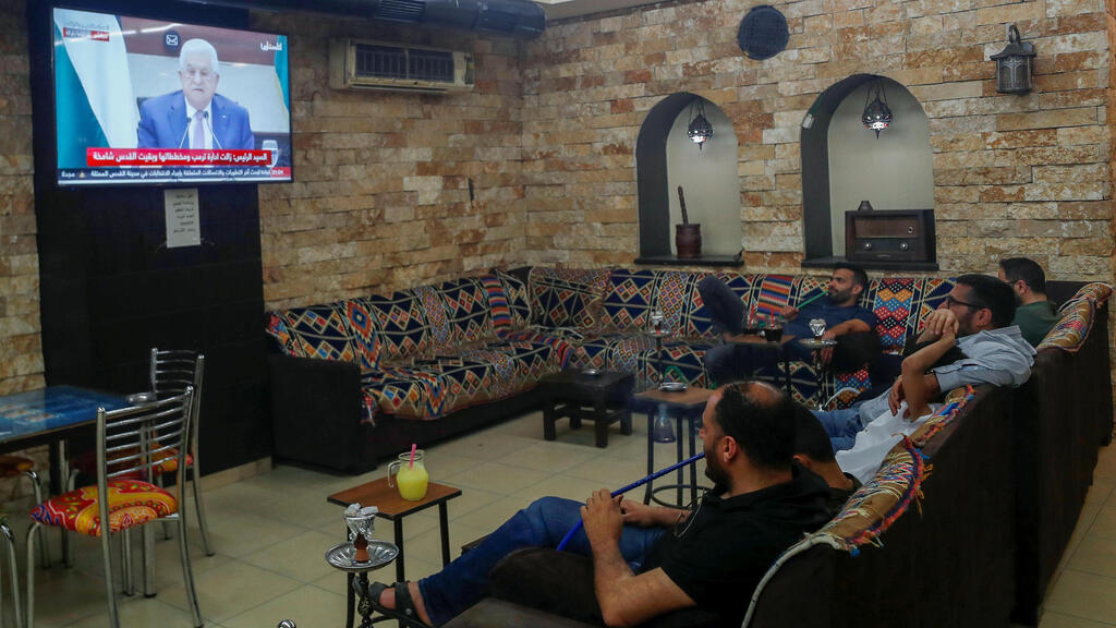 יושבים בית קפה ברמאללה צופים בנאום של אבו מאזן