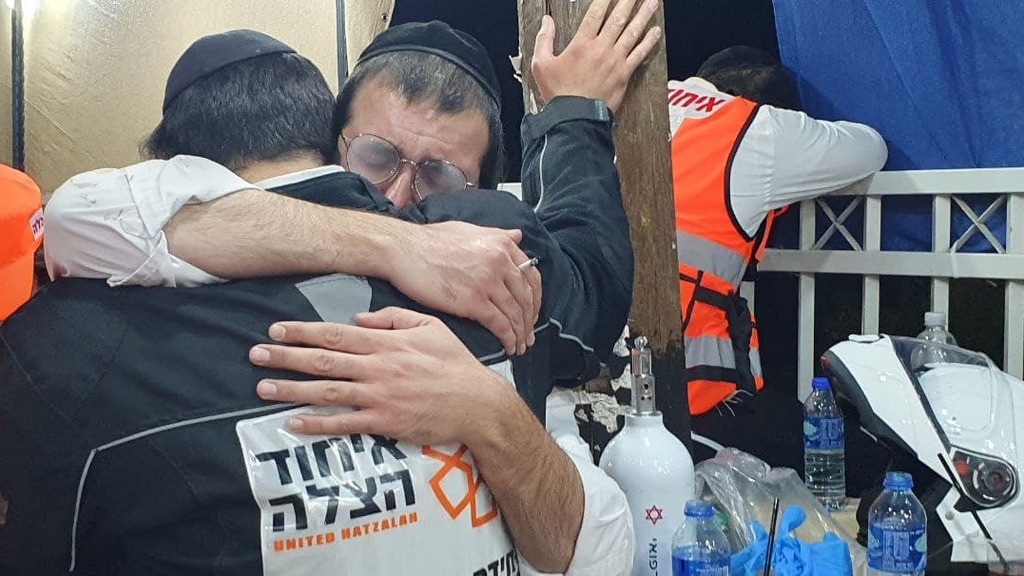 Rescue workers embrace after 45 people died in a stampede on Mount Meron late last month (Photo: Moshe Mizrahi) עשרות בני אדם נפגעו בדוחק הכבד באחד ממתחמי ההדלקה במתחם ההילולה בהר מירון