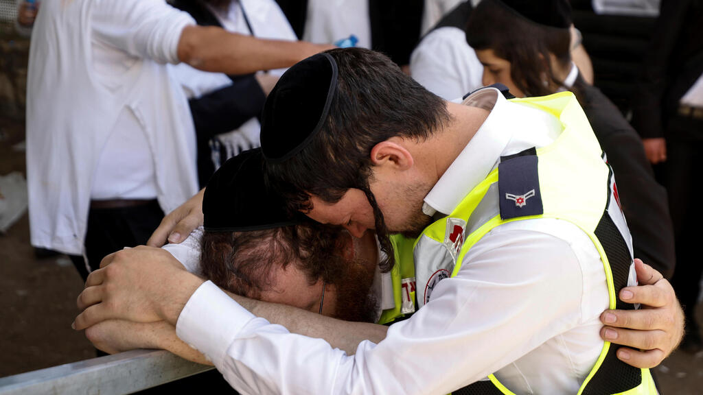 Emergency workers embrace in tears after the disaster at Meron (Photo: Reuters) נרות זיכרון בהר מירון
