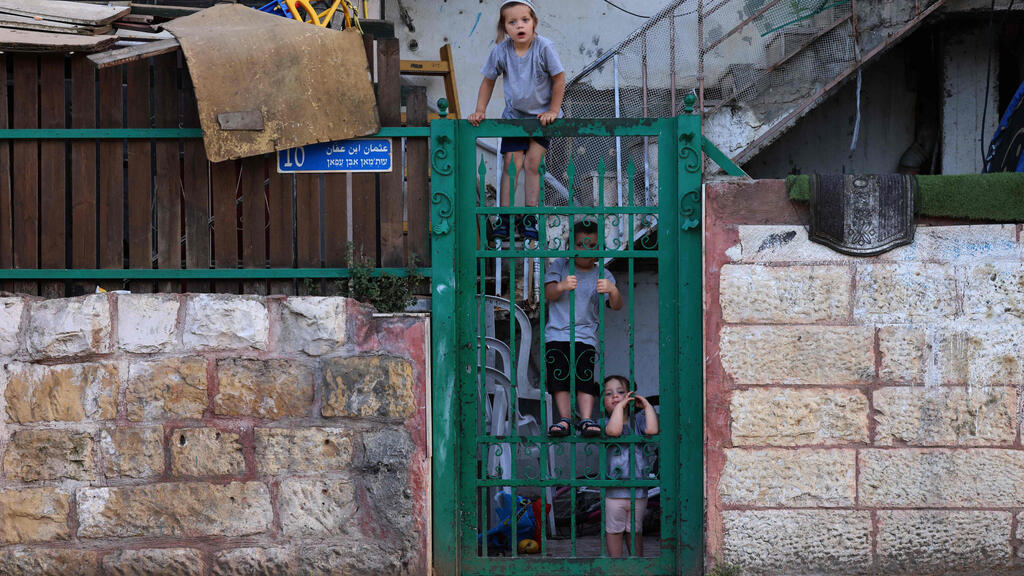 Israeli settler's children look at Palestinians gathering for an Iftar meal, the evening meal with which Muslims end their daily Ramadan fast at sunset, before a demonstration as Palestinian families face eviction, part of an ongoing effort by Jewish Israelis to take control of homes in the Sheikh Jarrah neighbourhood of occupied east Jerusalem 